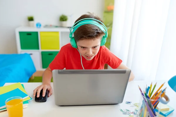 Niño en auriculares jugando videojuego en el ordenador portátil —  Fotos de Stock