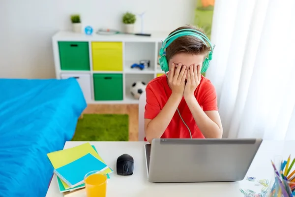 Chlapec ve sluchátkách hraje videohry na notebooku — Stock fotografie