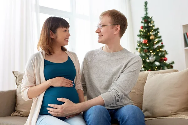 Pregnant wife with husband at home at christmas — Stock Photo, Image