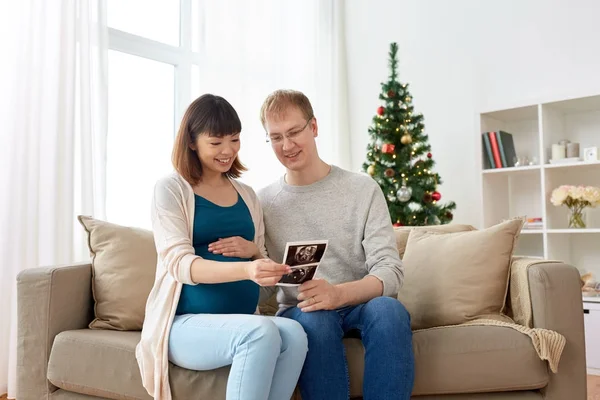 Happy couple with ultrasound images at christmas — Stock Photo, Image