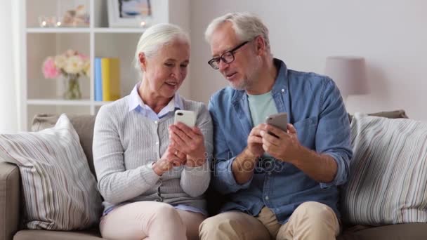 Feliz pareja de ancianos con teléfonos inteligentes en casa — Vídeos de Stock