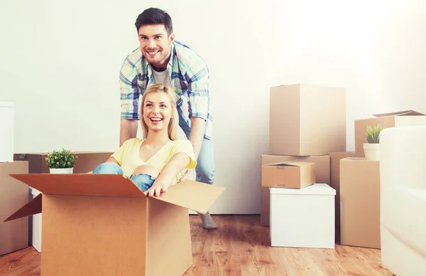 Feliz pareja divirtiéndose con cajas en nuevo hogar —  Fotos de Stock