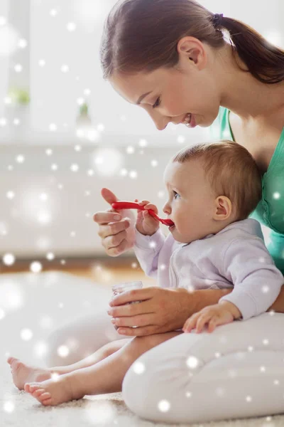 Mother with spoon feeding little baby at home — Stock Photo, Image