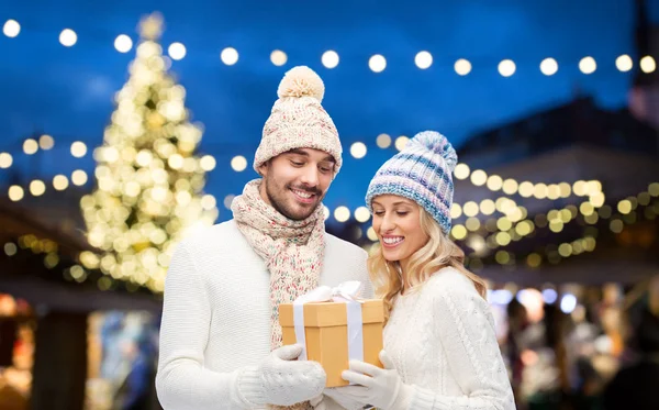 Coppia felice con scatola regalo sopra luci di Natale — Foto Stock