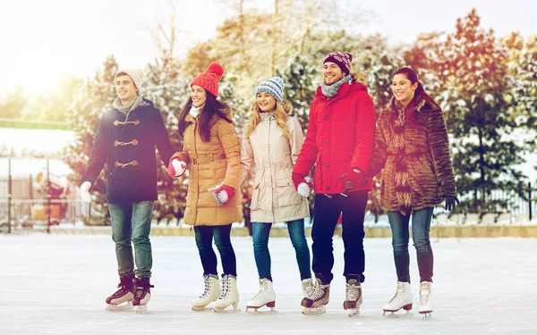Happy friends ice skating on rink outdoors — Stock Photo, Image