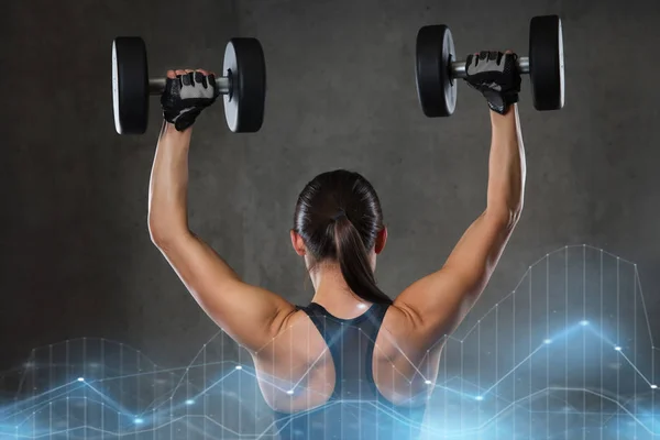 Mujer joven flexionando los músculos con pesas en el gimnasio —  Fotos de Stock