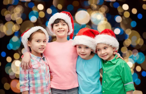 Niños pequeños y felices en sombreros de santa abrazo —  Fotos de Stock