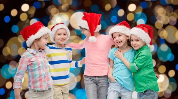 Happy little children in santa hats hugging — Stock Photo, Image