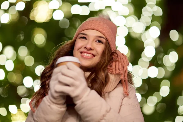 Gelukkige vrouw met koffie over Kerstverlichting — Stockfoto