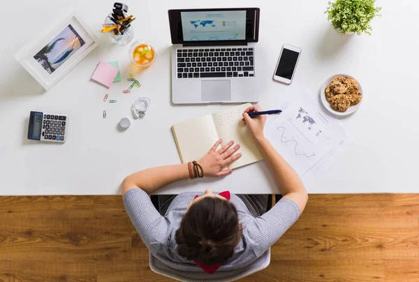 Vrouw met laptop schrijven naar notebook op kantoor — Stockfoto