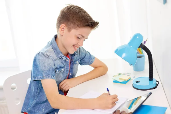 Menino estudante feliz escrevendo para notebook em casa — Fotografia de Stock