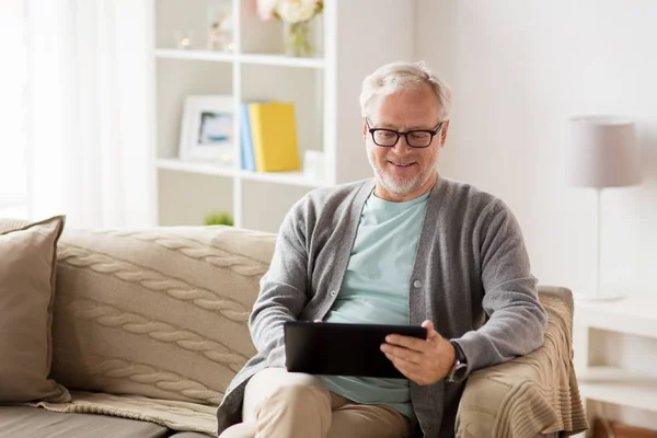Uomo anziano con tablet pc seduto sul divano a casa — Foto Stock