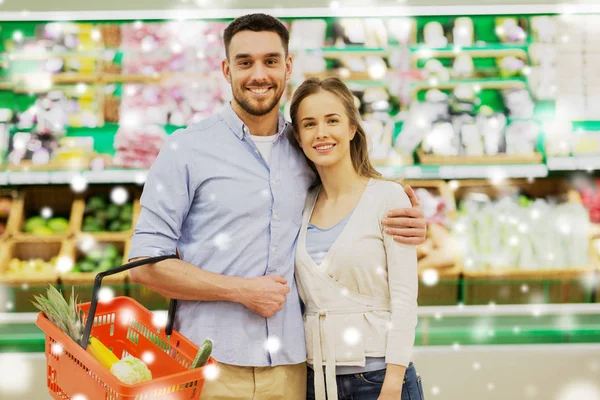 Coppia felice con cesto di cibo al negozio di alimentari — Foto Stock