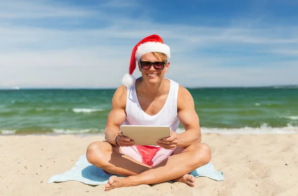 Счастливый человек с планшетным компьютером на пляже на Рождество — стоковое фото