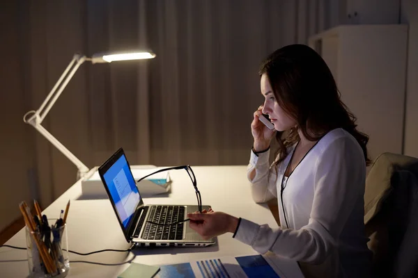 Mulher com laptop chamando no smartphone no escritório — Fotografia de Stock