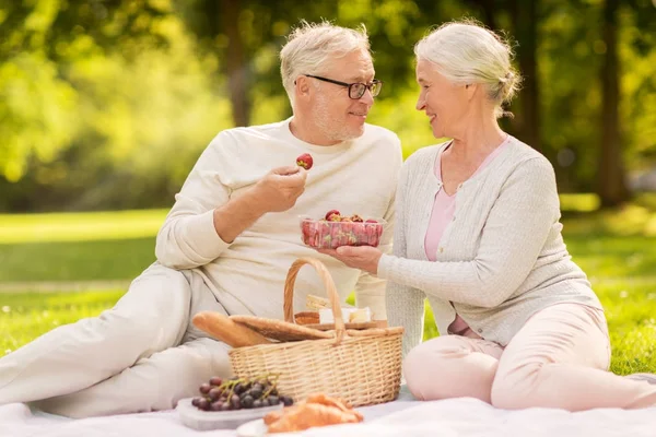 Старша пара з полуницею на пікніку в парку — стокове фото