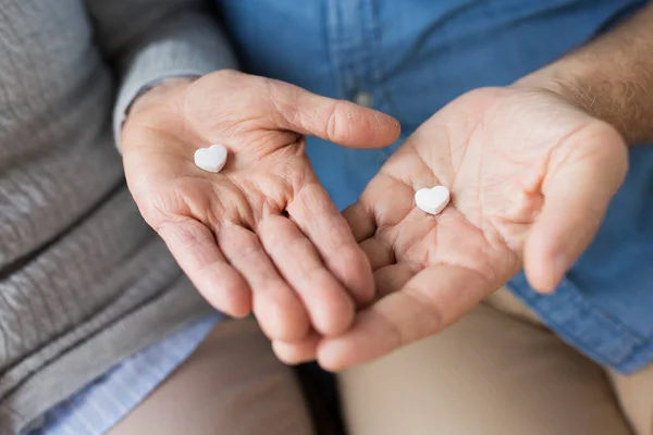 Close up of couple hands with heart shaped pill — Stock Photo, Image