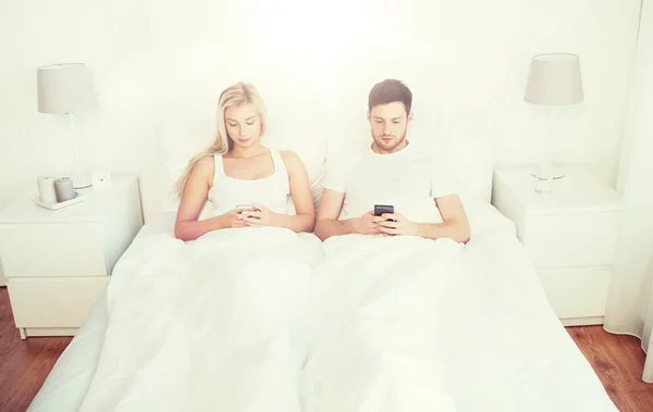 Coppia con smartphone a letto — Foto Stock