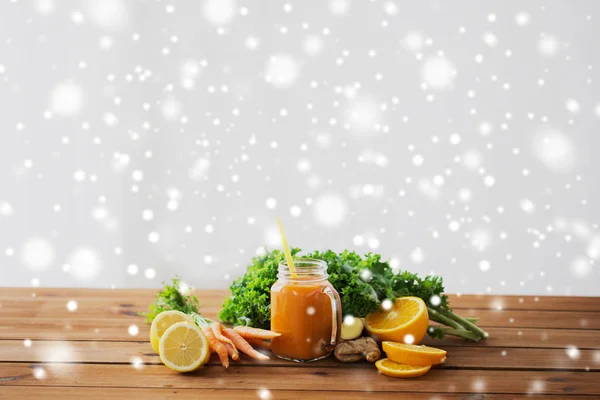 Glass jug of carrot juice, fruits and vegetables — Stock Photo, Image