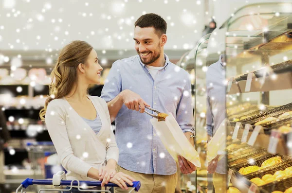 Gelukkige paar met winkelwagentje in supermarkt — Stockfoto
