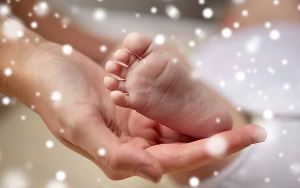 Крупним планом новонароджені ноги в руках матері — стокове фото