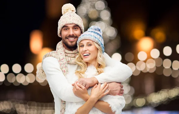 Gelukkige paar knuffelen over Kerstverlichting — Stockfoto