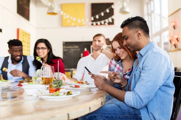 Happy friends with smartphones at restaurant — Stock Photo, Image
