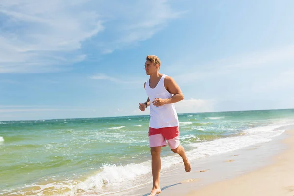 Šťastný muž běží podél letní pláž — Stock fotografie