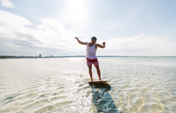 Junger Mann reitet auf Skimboard am Sommerstrand — Stockfoto