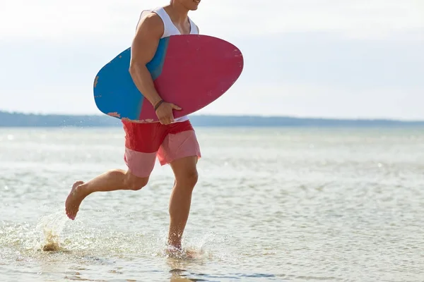 Glücklicher junger Mann mit Skimboard am Sommerstrand — Stockfoto