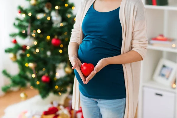 Close up af gravid kvinde med hjerte til jul - Stock-foto