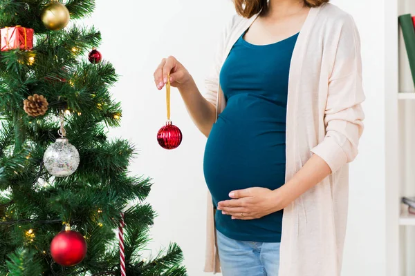妊娠中の女性クリスマスツリーを飾る — ストック写真