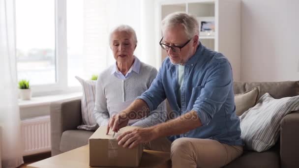 Senior couple with delivery note opening parcel — Stock Video