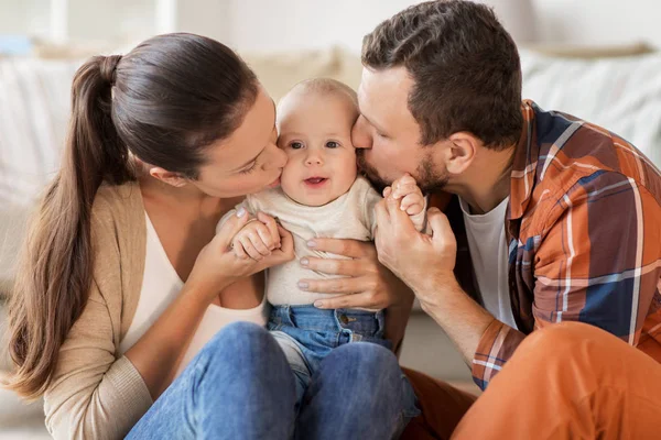 Счастливые мать и отец целует ребенка дома — стоковое фото