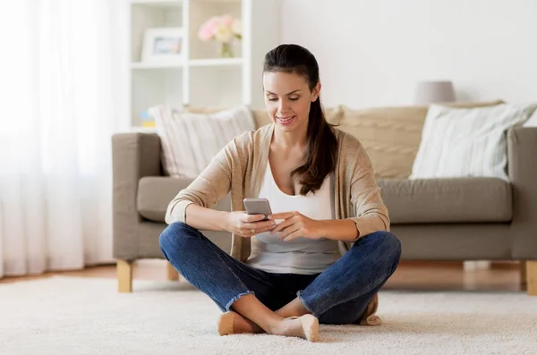 Glückliche Frau schreibt SMS auf Smartphone zu Hause — Stockfoto