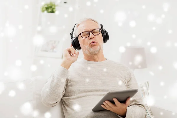 Hombre mayor con tablet PC y auriculares en casa — Foto de Stock