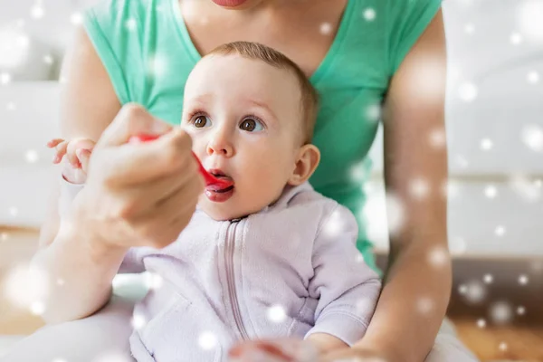 Mother with spoon feeding little baby at home — Stock Photo, Image