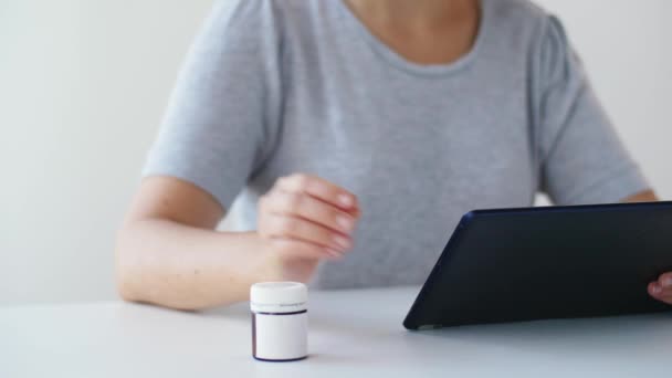 Vrouw met kruik van geneeskunde pillen en tablet pc — Stockvideo