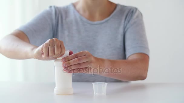 Vrouw gieten siroop uit fles naar geneeskunde cup — Stockvideo