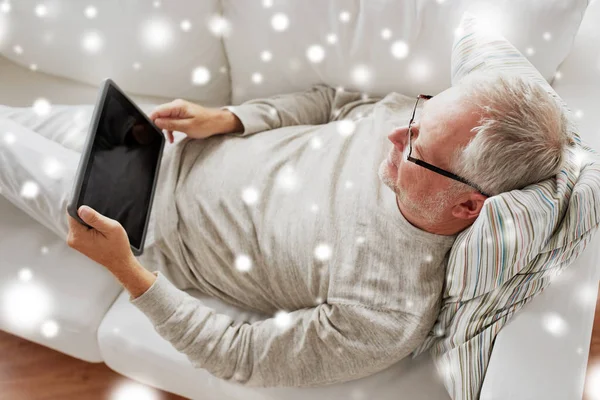 Senior man with tablet pc lying on sofa at home — стоковое фото