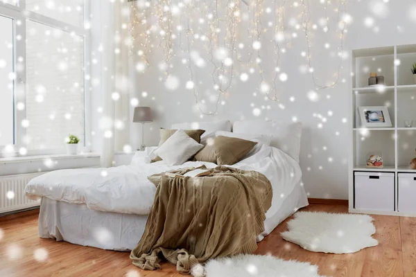 Спальня с кроватью и гирляндой на Рождество дома — стоковое фото