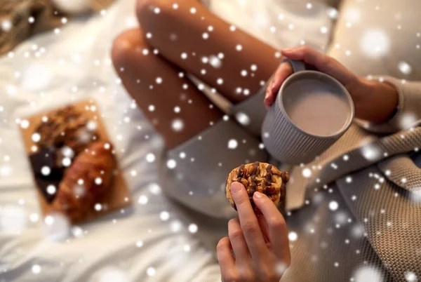 Close up of woman with cococoa cup and cookie in bed — стоковое фото