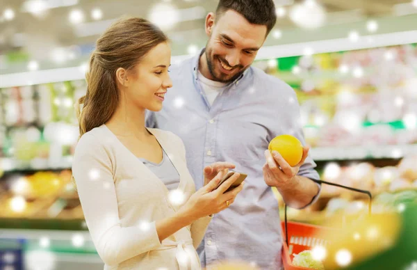 Coppia con smartphone acquistare arance al supermercato — Foto Stock