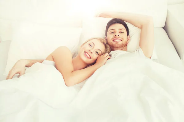 Casal feliz deitado na cama em casa — Fotografia de Stock