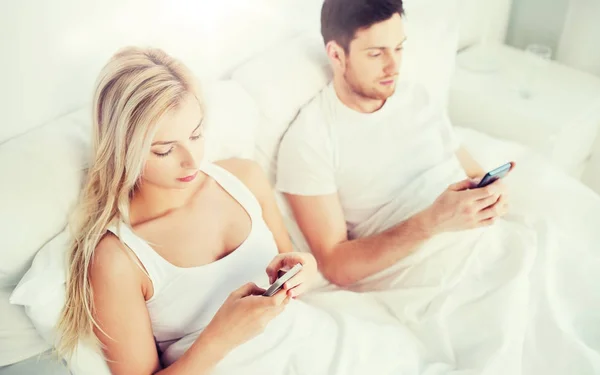 Casal com smartphones na cama — Fotografia de Stock