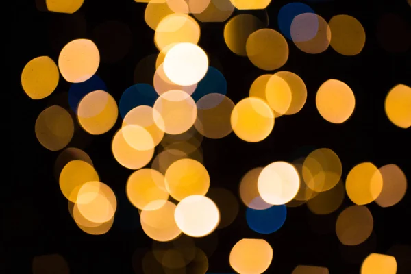 Luzes douradas borradas sobre fundo escuro — Fotografia de Stock