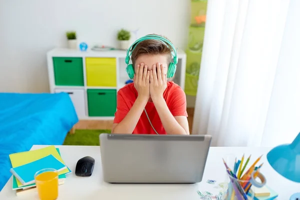 Chlapec ve sluchátkách hraje videohry na notebooku — Stock fotografie