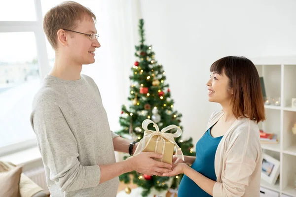 Marido dando regalo de Navidad a la esposa embarazada — Foto de Stock