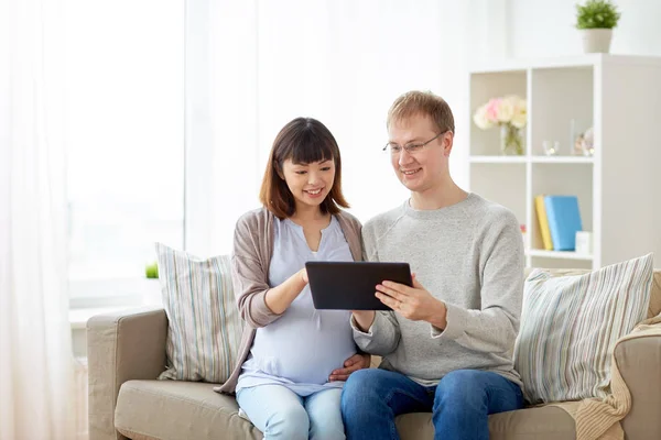 Mąż i żona w ciąży z komputera typu tablet w domu — Zdjęcie stockowe