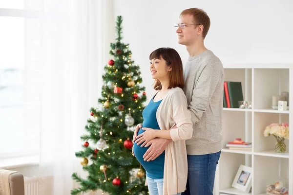 Беременная жена с мужем дома на Рождество — стоковое фото